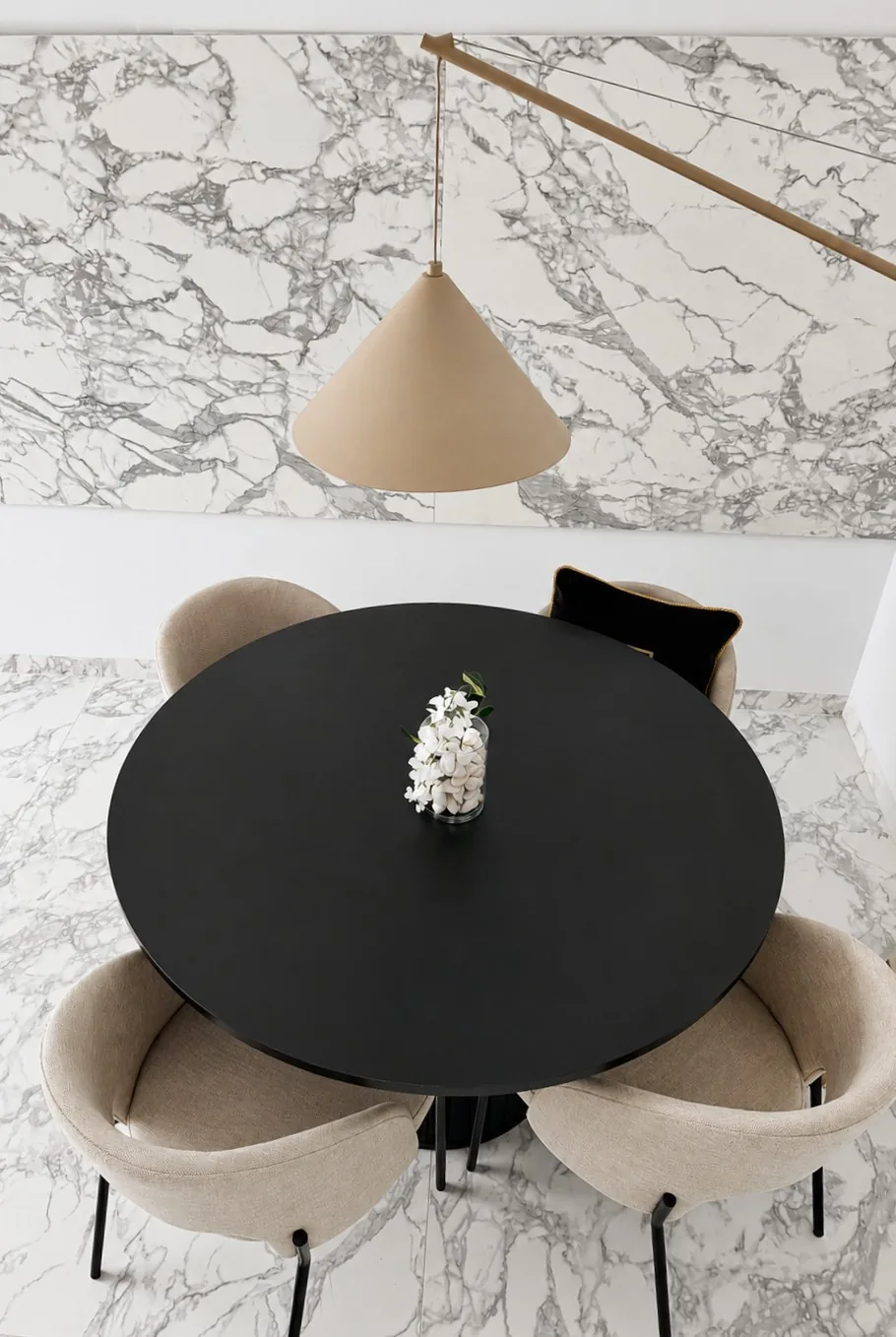 Elegancki salon z okrągłym czarnym stołem, tapicerowanymi fotelami i marmurową ścianą w apartamencie na Teneryfie